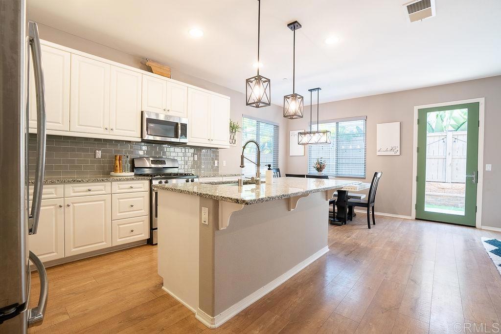 1132 Cherry Tree Lane Vista, CA 92084 - Photo 8 of 39 a kitchen with kitchen island granite countertop a sink counter top space and stainless steel appliances
