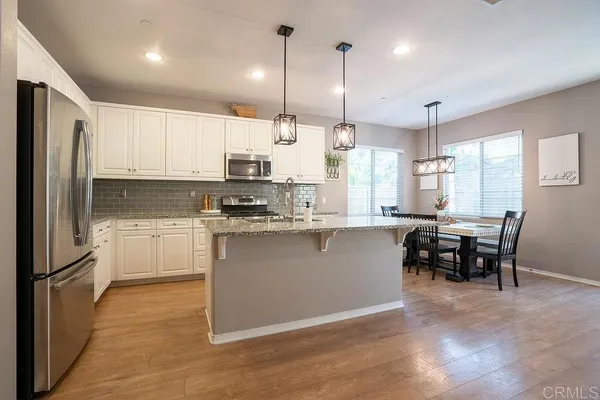 a kitchen with kitchen island granite countertop a table chairs microwave and cabinets