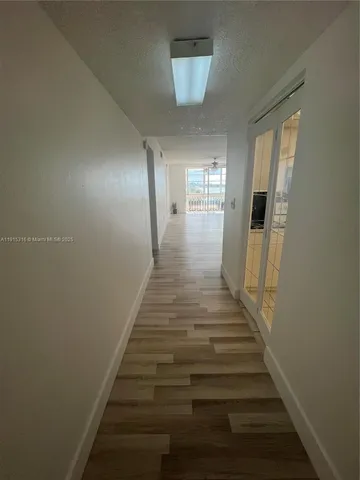 a view of a hallway with wooden floor and entryway