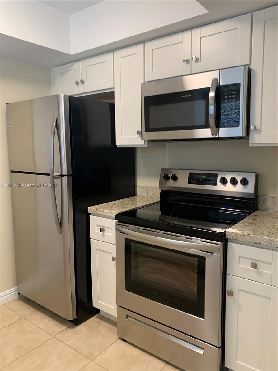 3500 Harrison Street, Unit 8 Hollywood, FL 33021 - Photo 3 of 59 a kitchen with stainless steel appliances a stove a microwave and cabinets