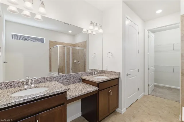 a bathroom with a granite countertop sink a mirror and a shower