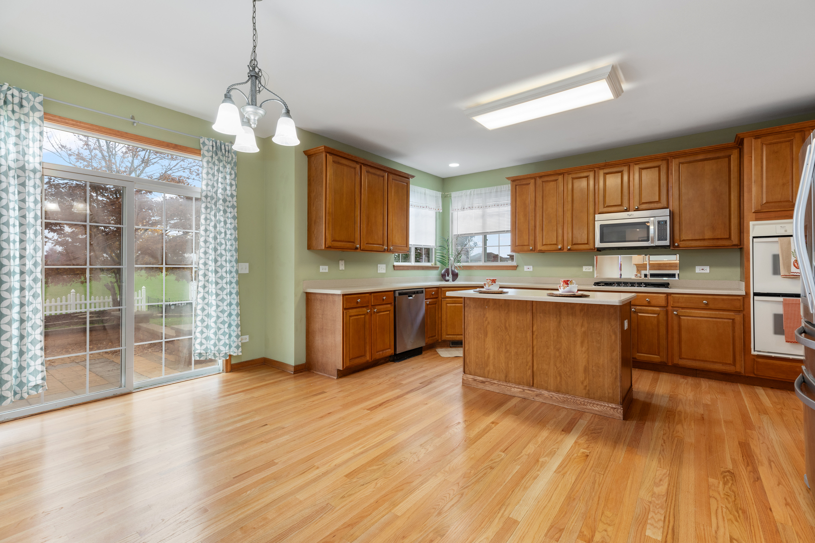 25231 Gettysburg Road Plainfield, IL 60544 - Photo 9 of 30 a kitchen with stainless steel appliances granite countertop a stove top oven a sink dishwasher a refrigerator and a dining table with wooden floor
