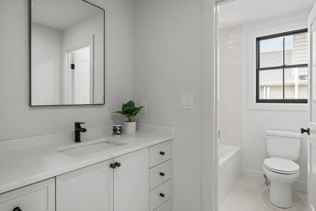 a bathroom with a toilet a sink a window and mirror