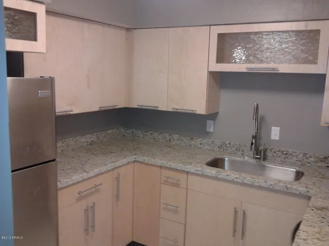 a kitchen with granite countertop white cabinets and a refrigerator