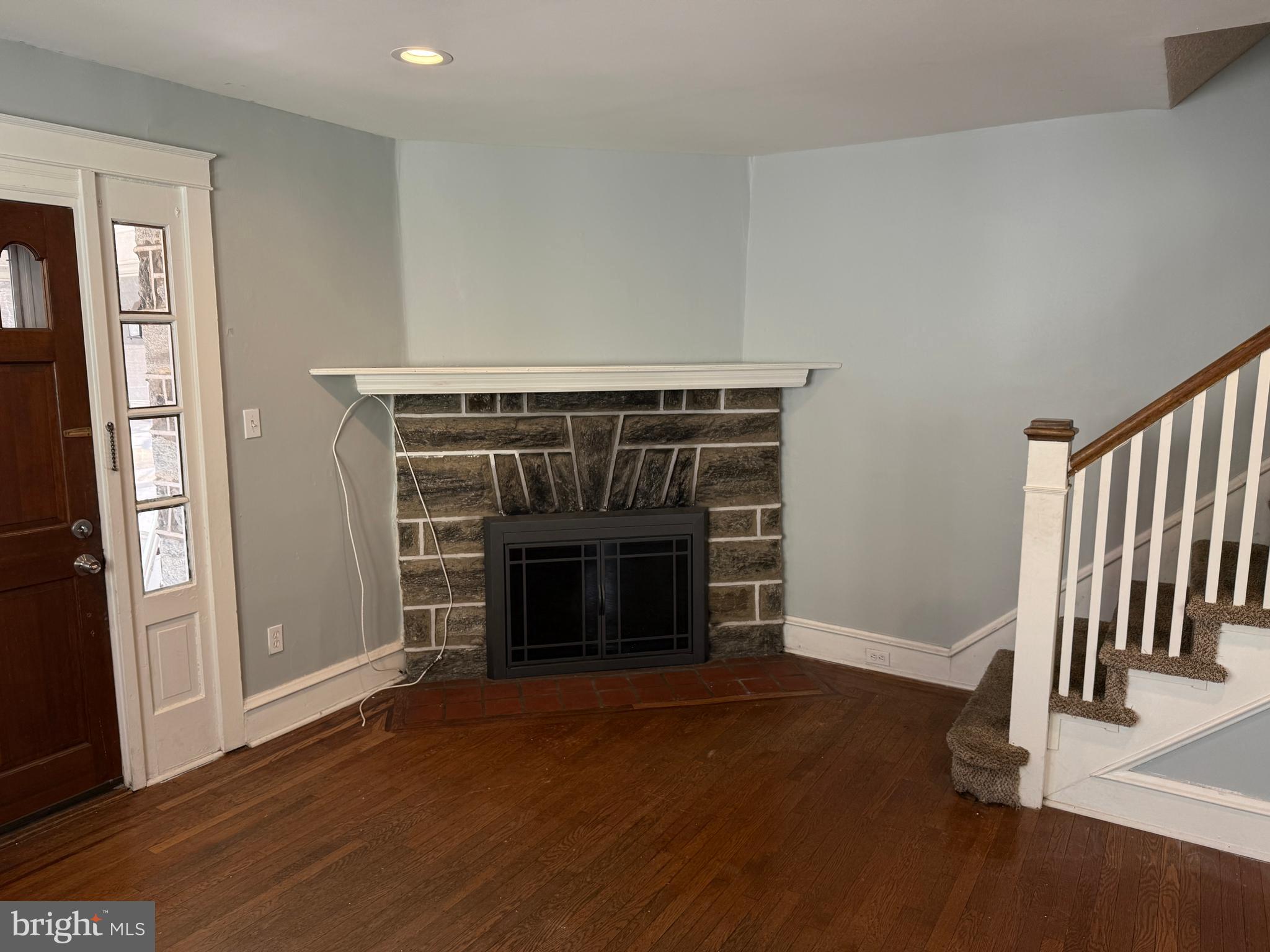 4049 Marshall Road Upper Darby, PA 19026 - Photo 4 of 26 a view of an empty room with wooden floor fireplace and a window