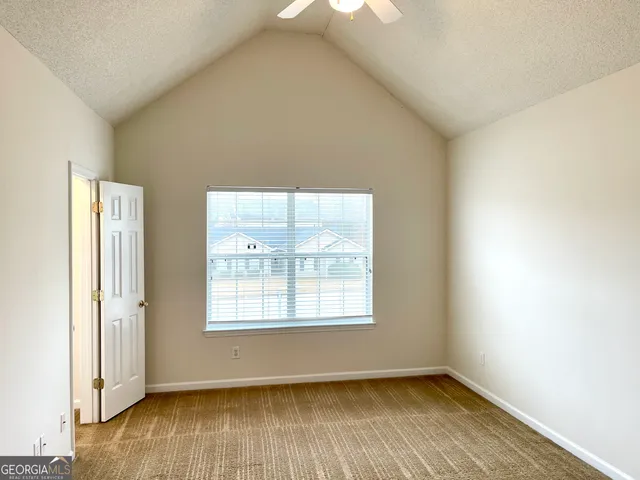 a view of empty room with wooden floor and bathroom