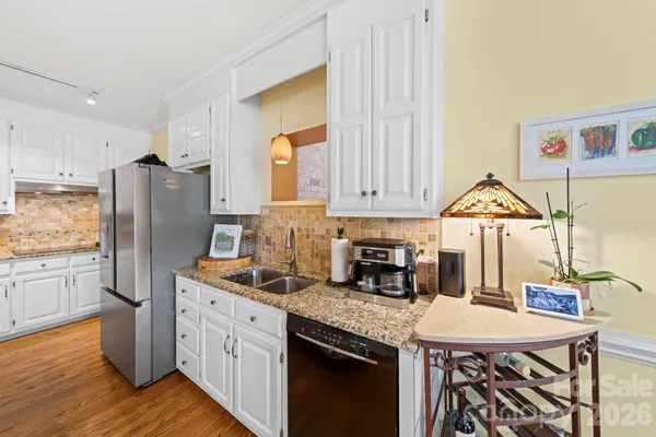 a kitchen with stainless steel appliances granite countertop a kitchen island hardwood floor sink stove and white cabinets