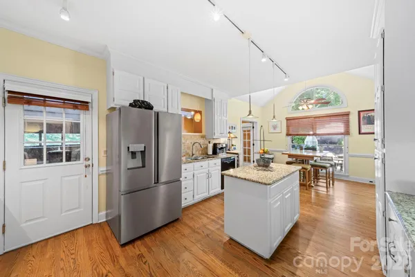 a kitchen with stainless steel appliances granite countertop a refrigerator a stove and a wooden floors