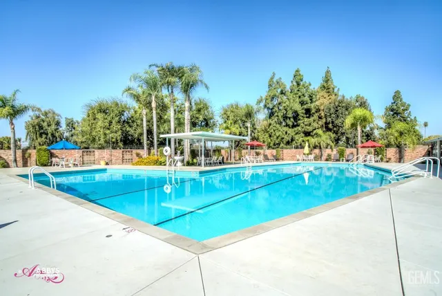 a view of a swimming pool with lawn chairs under an umbrella