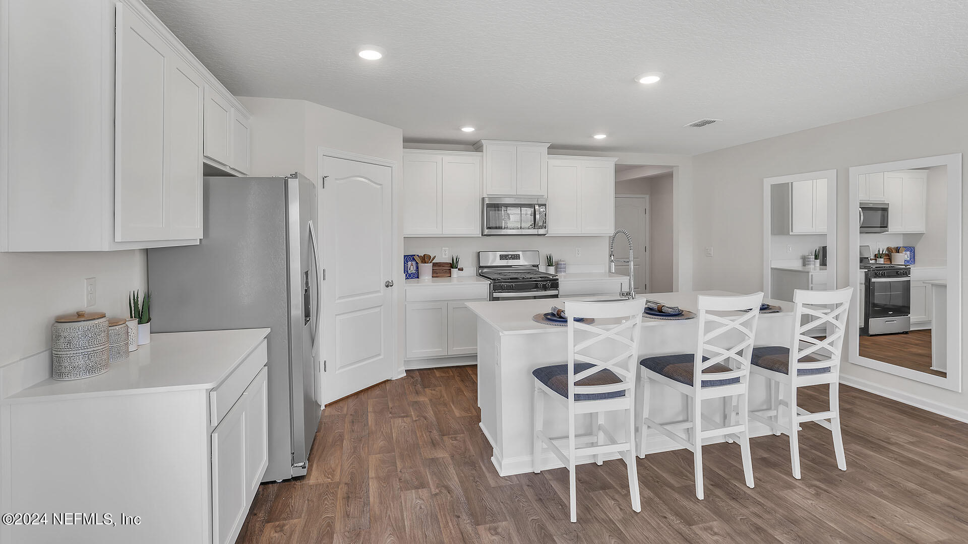 114 Hulett Wds Road Palm Coast, FL 32137 - Photo 9 of 36 a kitchen with stainless steel appliances kitchen island granite countertop a wooden floor and white cabinets