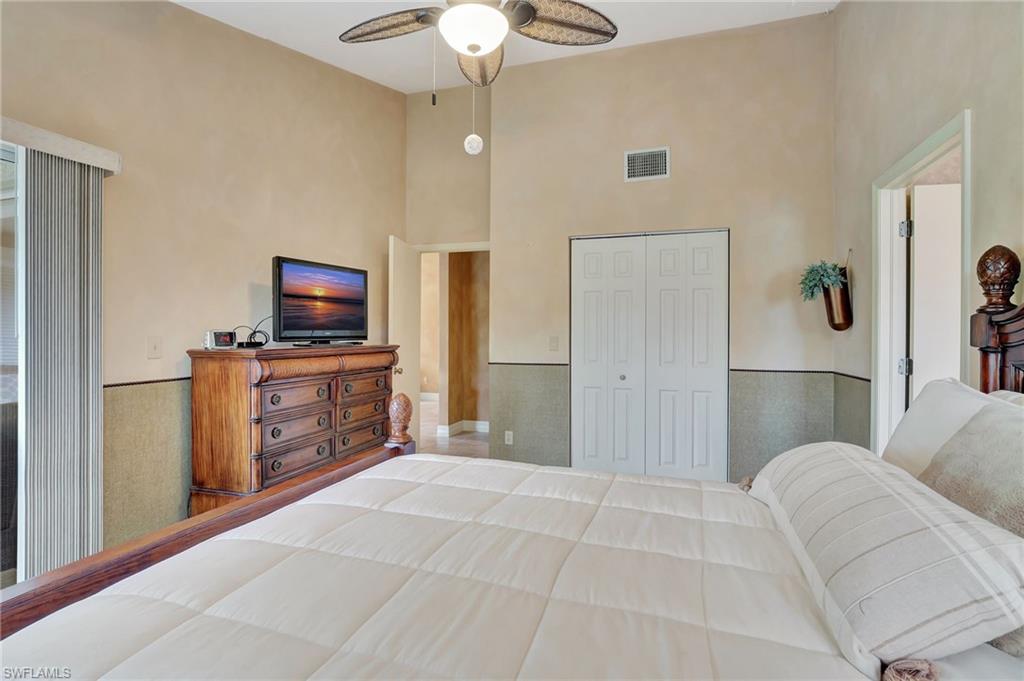 2103 Tama Circle, Unit 202 Naples, FL 34112 - Photo 18 of 28 a spacious bedroom with a bed and a flat screen tv