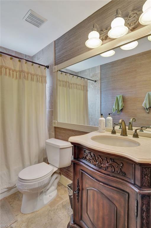 2103 Tama Circle, Unit 202 Naples, FL 34112 - Photo 23 of 28 a bathroom with a granite countertop toilet sink and mirror