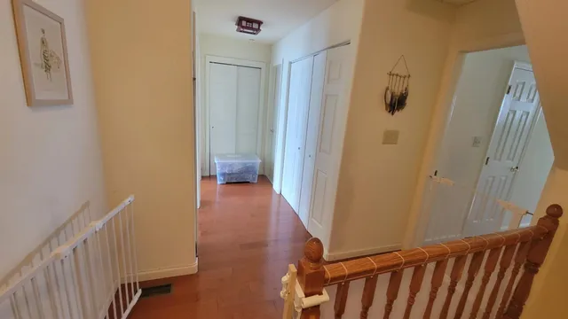 a view of a hallway with wooden floor and staircase