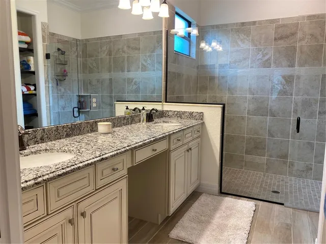 a bathroom with a granite countertop sink a mirror and a shower