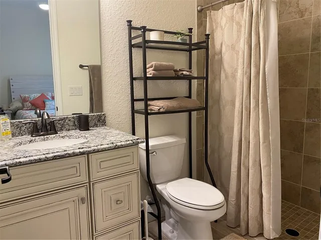 a bathroom with a granite countertop toilet sink and mirror