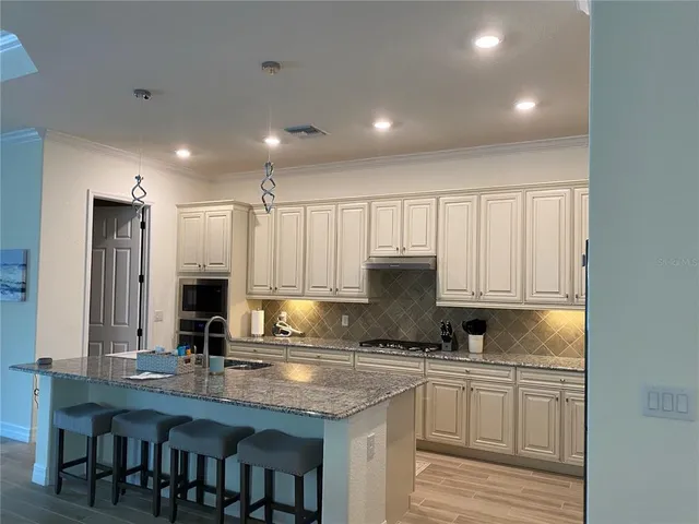 a kitchen with kitchen island granite countertop a sink a center island stainless steel appliances and cabinets