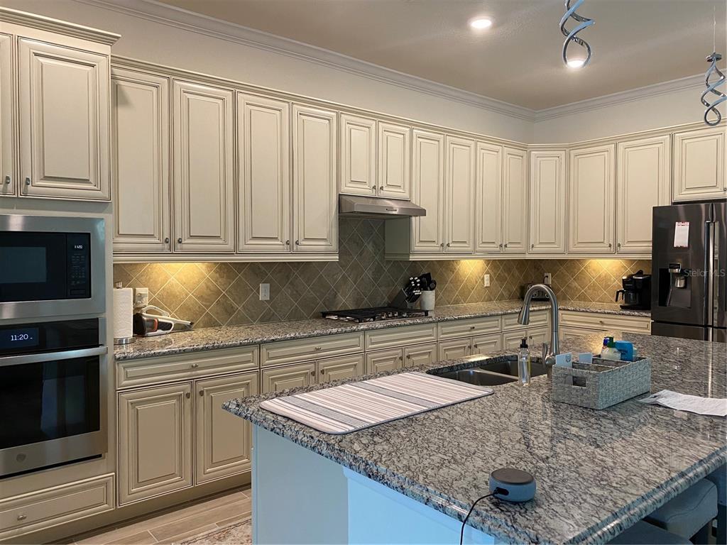 17525 Hickok Belt Loop Bradenton, FL 34211 - Photo 7 of 31 a kitchen with granite countertop a sink stove and cabinets