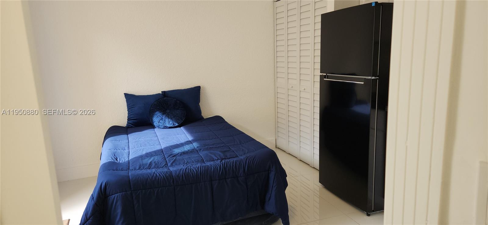 17930 Southwest 136th Avenue, Unit B Miami, FL 33177 - Photo 4 of 4 a bedroom with a bed and a refrigerator