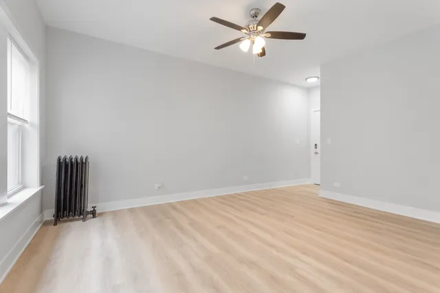 an empty room with a window and a fan