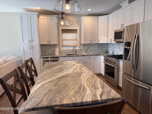 a kitchen with granite countertop a stove sink and refrigerator