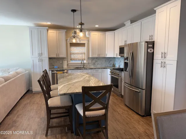 a kitchen with stainless steel appliances a dining table chairs refrigerator and microwave