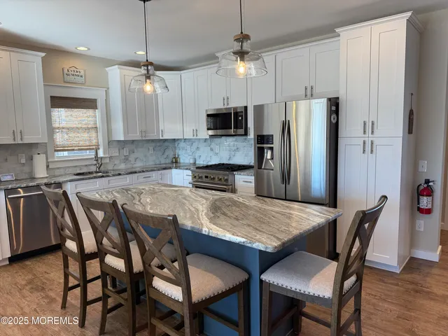 a kitchen with stainless steel appliances granite countertop a dining table chairs refrigerator and fireplace