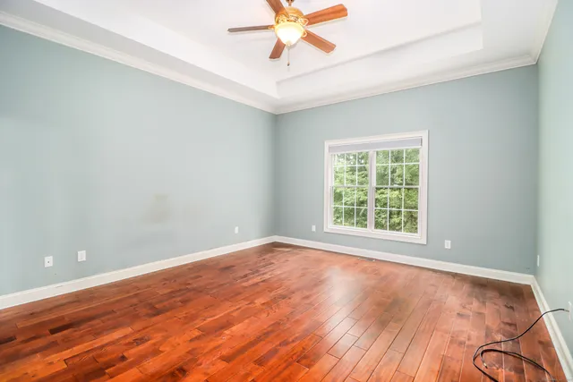a view of an empty room with window and wooden floor