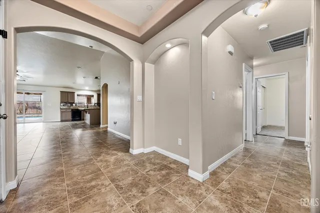 an empty room with kitchen view and a ceiling fan