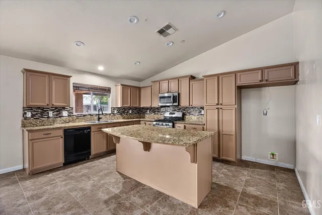 a kitchen with kitchen island granite countertop a sink stainless steel appliances and cabinets