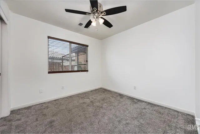 an empty room with a ceiling fan and carpet
