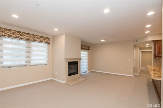 an empty room with windows and fireplace