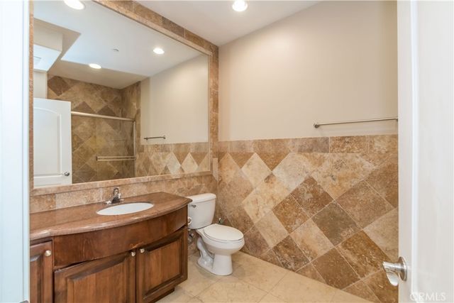 a bathroom with a granite countertop sink toilet a mirror and shower curtain