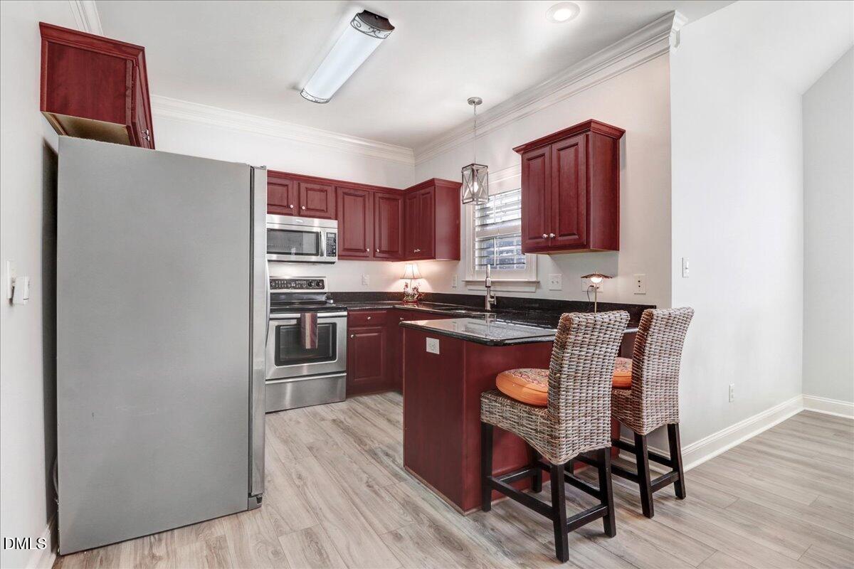 22 Quebec Drive Selma, NC 27576 - Photo 26 of 39 a kitchen with stainless steel appliances granite countertop a stove a refrigerator a sink a dining table and chairs with wooden floor