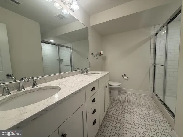a spacious bathroom with a double vanity sink a toilet and a mirror
