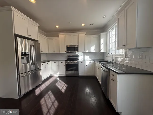 a kitchen with granite countertop a refrigerator stove and sink