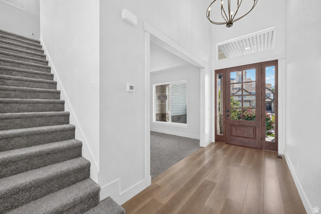1002 West Temple Rim Lane Payson, UT 84651 - Photo 7 of 68 Entryway featuring wood-finish flooring, a wood-panel front door with glass inserts and sidelights, and a high ceiling with a contemporary chandelier