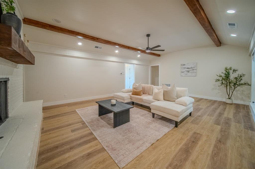 5125 Ashbrook Road Dallas, TX 75227 - Photo 10 of 34 Vaulted ceiling with exposed wood beams, wood-finish flooring, recessed lighting, and a white brick fireplace with a wood mantel