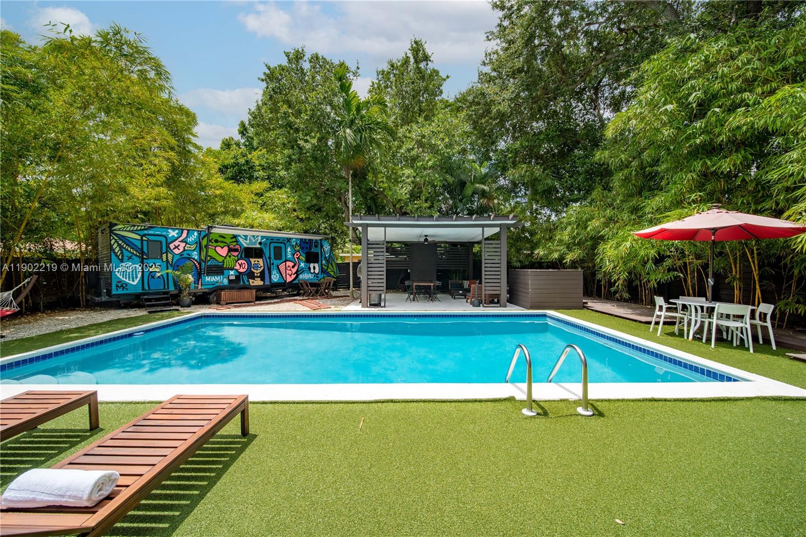 710 Northeast 141st Street North Miami, FL 33161 - Photo 35 of 78 a view of a swimming pool with a table and chairs under an umbrella