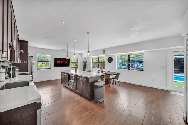 a kitchen with stainless steel appliances a dining table chairs stove refrigerator and cabinets