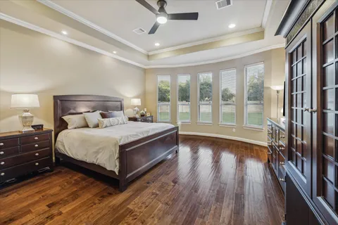 a bedroom with a large bed and a large window with wooden floor
