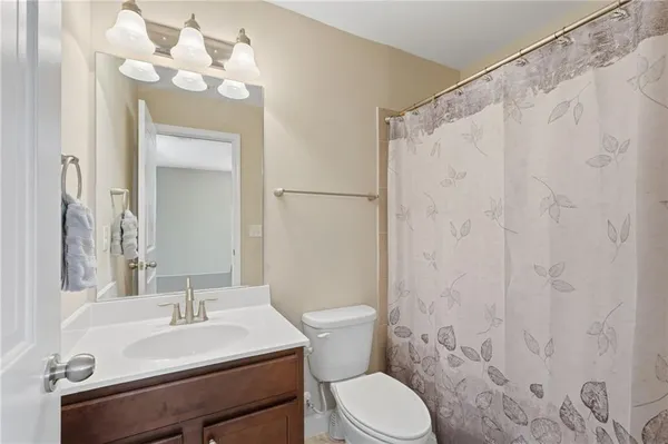 a bathroom with a sink a toilet a mirror and shower curtain