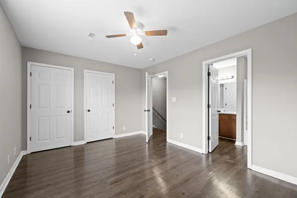 an empty room with wooden floor and a ceiling fan