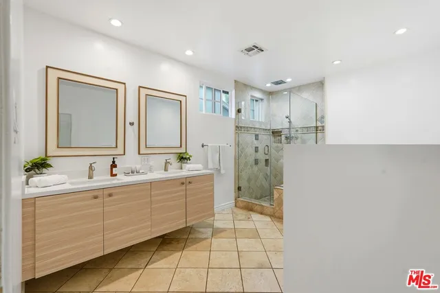 a bathroom with a double vanity sink mirror and shower