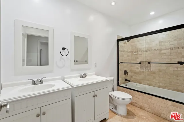 a bathroom with a toilet a sink a mirror a shower a vanity and window