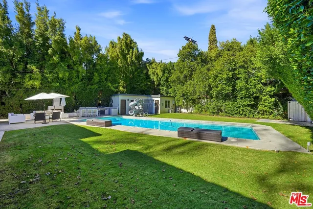 a view of a swimming pool with a yard chairs and floor to ceiling window