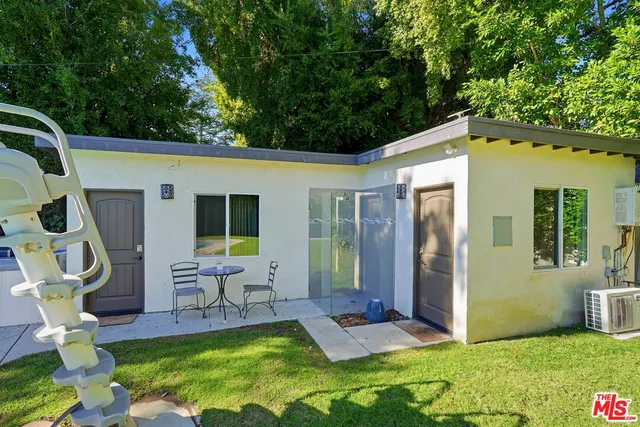 a view of a chair and table in backyard of the house