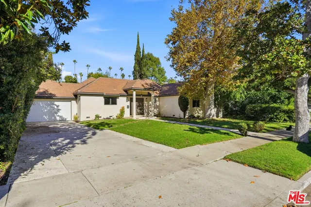 a front view of a house with a yard and trees