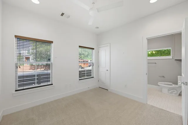 a view of an empty room with a window and bathroom
