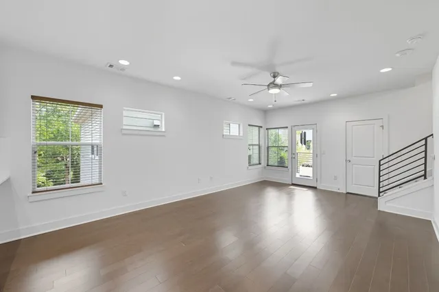 a view of an empty room with a kitchen and a window