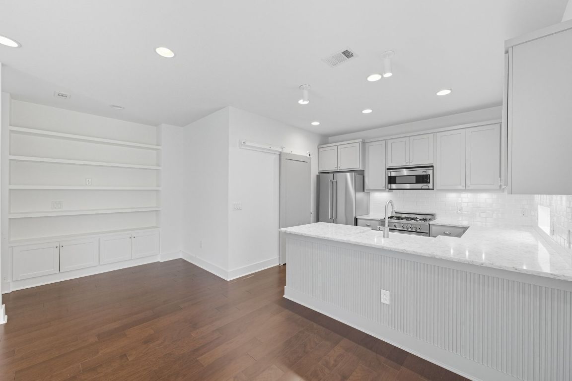 1010 Muse Lane, Unit 15 Austin, TX 78702 - Photo 5 of 22 a kitchen with stainless steel appliances granite countertop a sink a stove a refrigerator with white cabinets